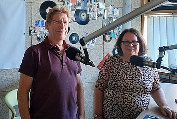 Volksanwalt Bernhard Achitz und Moderatorin Margit Wolfsberger, hinter Mikrofonen im Studio von Campus & City Radio St. Pölten