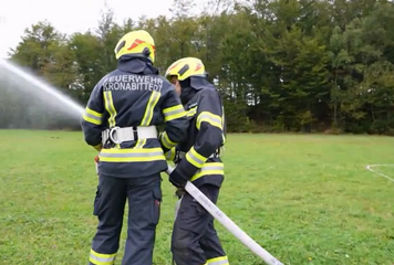Mitglieder der Freiwilligen Feuerwehr mit einem Löschschlauch bei einer Übung