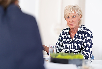 Volksanwältin Gaby Schwarz im Gespräch mit einer zweiten Person, an einem Tisch sitzend