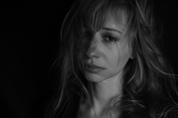 Schwarz-Weiß-Portraitfoto einer weinenden jungen Frau mit langen Haaren.